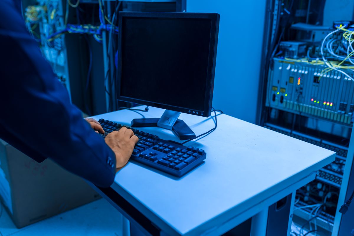 An IT technician works in a server room, illustrating infrastructure protection